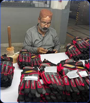 Worker inspecting stacks of red and black industrial gloves