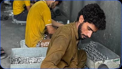 Workers sorting metal components on a workshop floor
