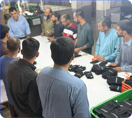 Workers reviewing branded work gloves during a factory briefing